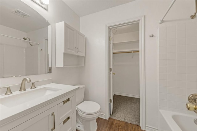 full bathroom with vanity, toilet, tiled shower / bath combo, and wood-type flooring