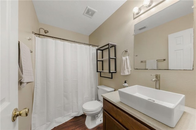 bathroom with hardwood / wood-style flooring, vanity, toilet, and curtained shower