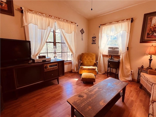 living area with a wealth of natural light, baseboards, wood finished floors, and vaulted ceiling