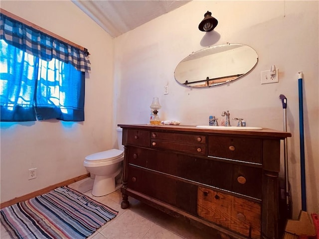 half bathroom featuring tile patterned flooring, toilet, vanity, and baseboards