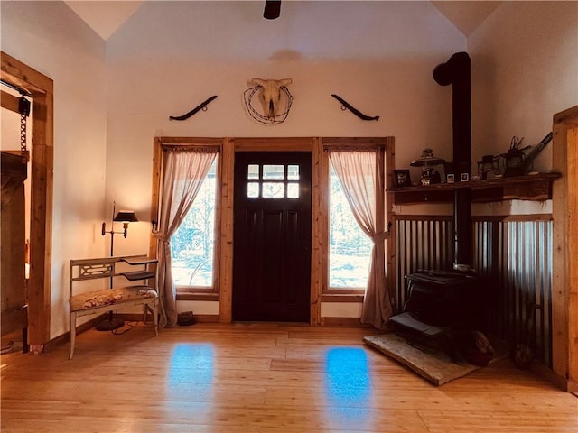 entrance foyer with plenty of natural light, a wood stove, and wood finished floors