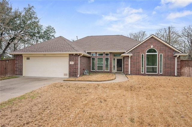 single story home with driveway, a shingled roof, an attached garage, fence, and brick siding