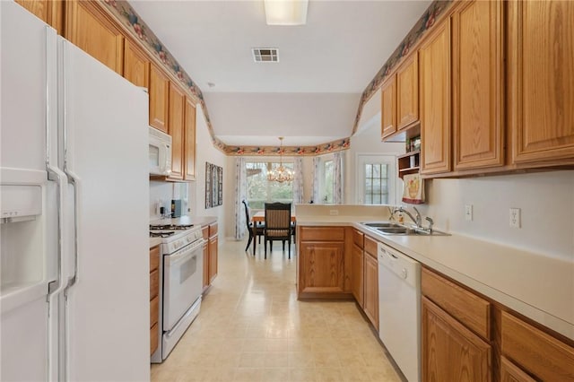 kitchen with hanging light fixtures, sink, a notable chandelier, and white appliances