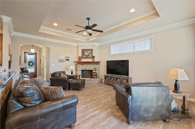 living room with ceiling fan, light hardwood / wood-style floors, a raised ceiling, and ornamental molding