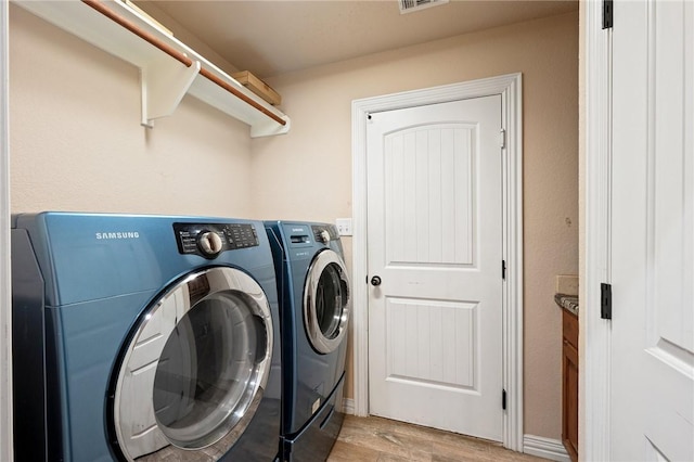 laundry area with light wood-type flooring and separate washer and dryer