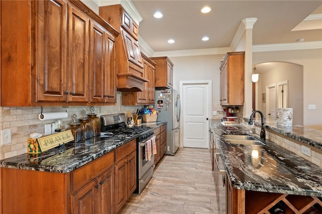 kitchen with appliances with stainless steel finishes, tasteful backsplash, dark stone countertops, and sink