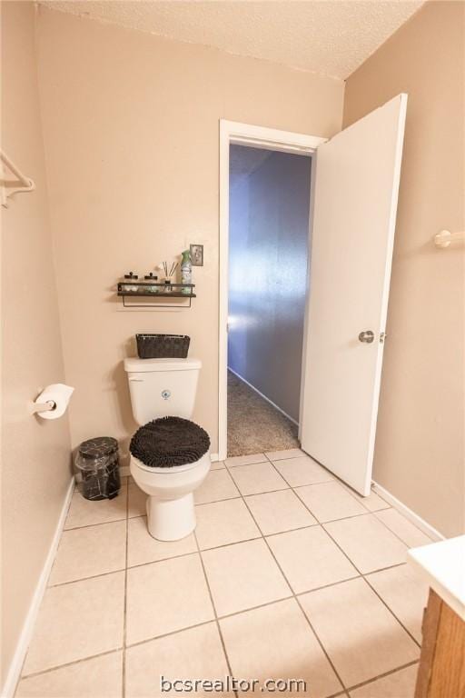 bathroom with tile patterned flooring, vanity, a textured ceiling, and toilet