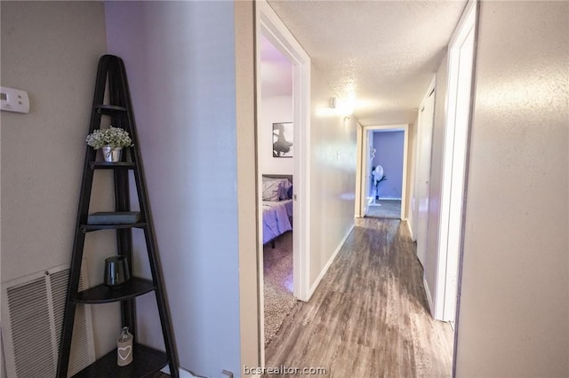 hall with wood-type flooring and a textured ceiling