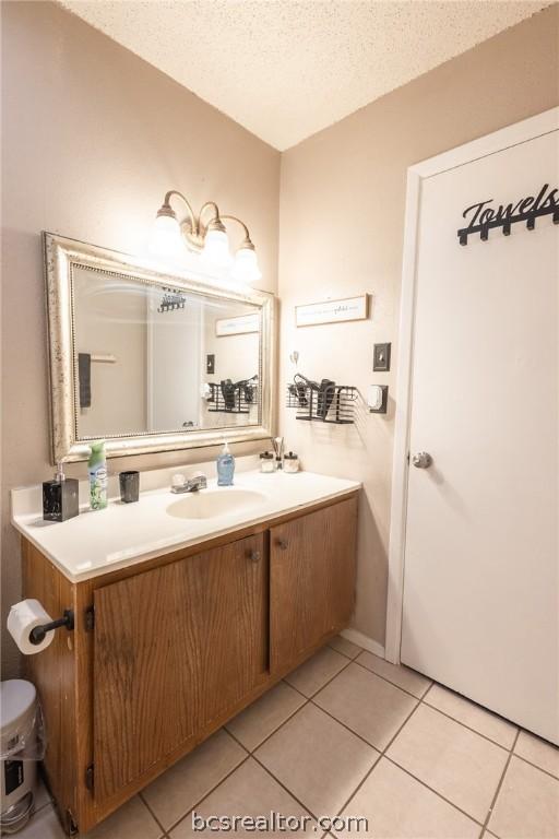 bathroom with tile patterned flooring, vanity, and a textured ceiling