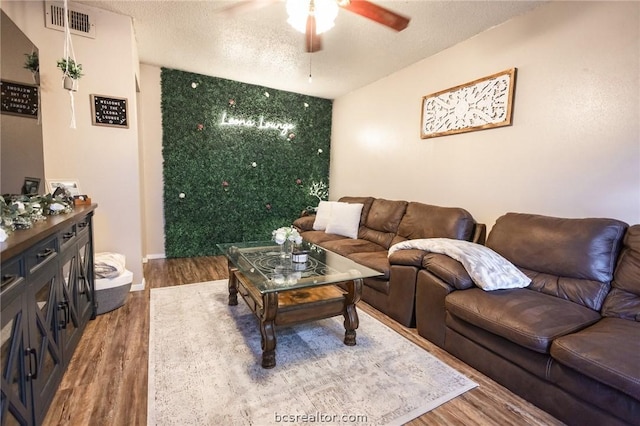 living room with ceiling fan, hardwood / wood-style floors, and a textured ceiling