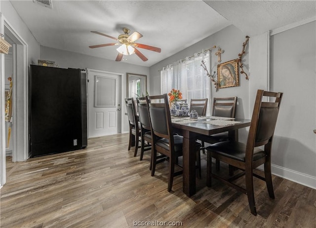 dining area with ceiling fan, a textured ceiling, and hardwood / wood-style flooring