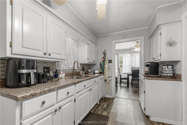 kitchen featuring hardwood / wood-style flooring, crown molding, white cabinetry, and sink