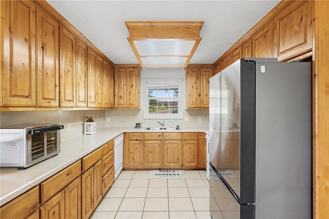 1819 Cheryl Dr, Caldwell, TX 77836 - kitchen featuring freestanding refrigerator, light tile patterned flooring, dishwasher, light countertops, and brown cabinets