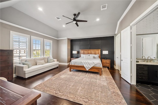 bedroom with dark wood finished floors, visible vents, vaulted ceiling, a sink, and baseboards