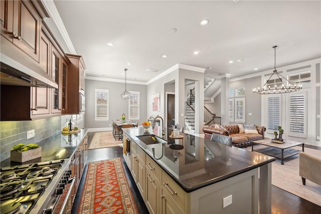 kitchen with high end stainless steel range, tasteful backsplash, glass insert cabinets, a sink, and an island with sink