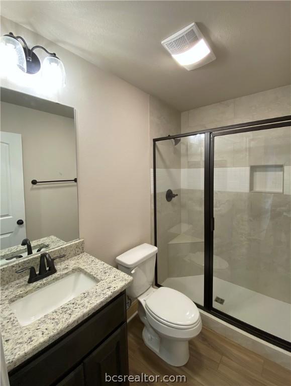 bathroom with vanity, hardwood / wood-style flooring, toilet, and an enclosed shower