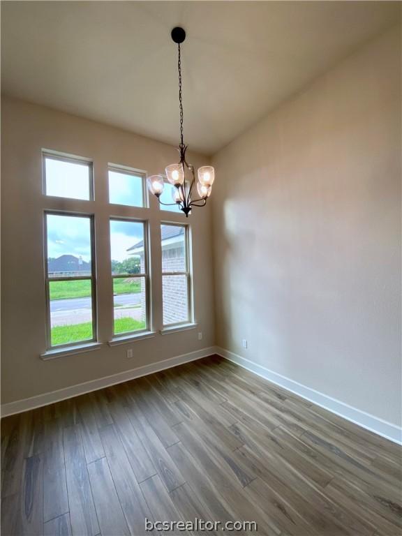 empty room with hardwood / wood-style floors and a notable chandelier