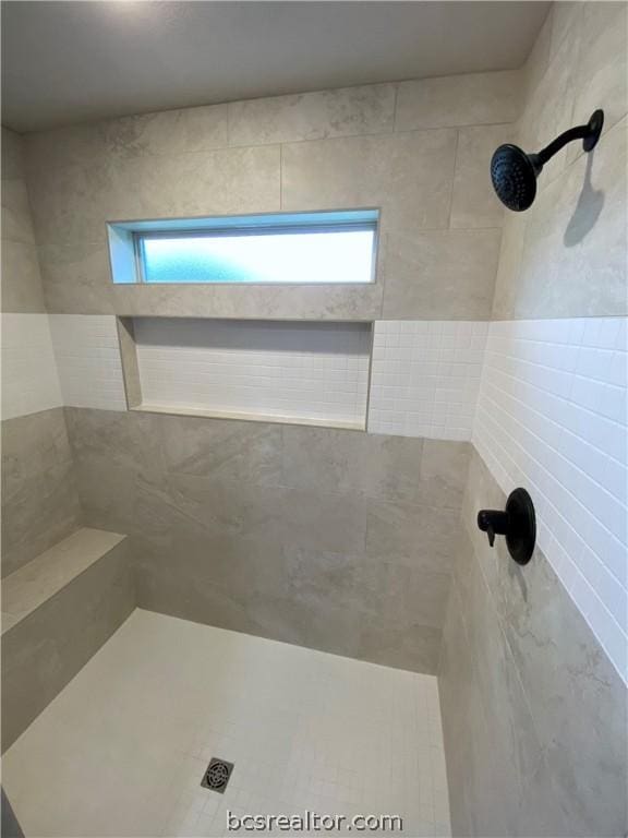 bathroom with a tile shower and tile walls