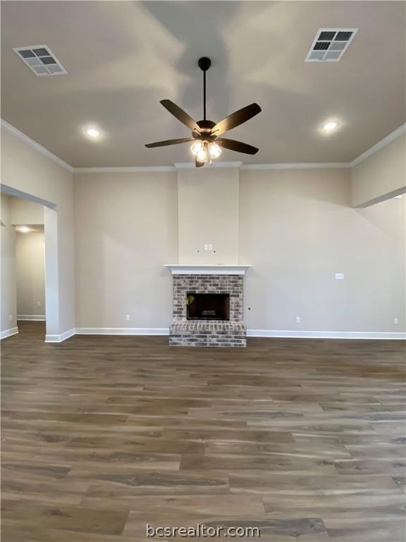 unfurnished living room featuring a fireplace, ceiling fan, dark hardwood / wood-style flooring, and crown molding