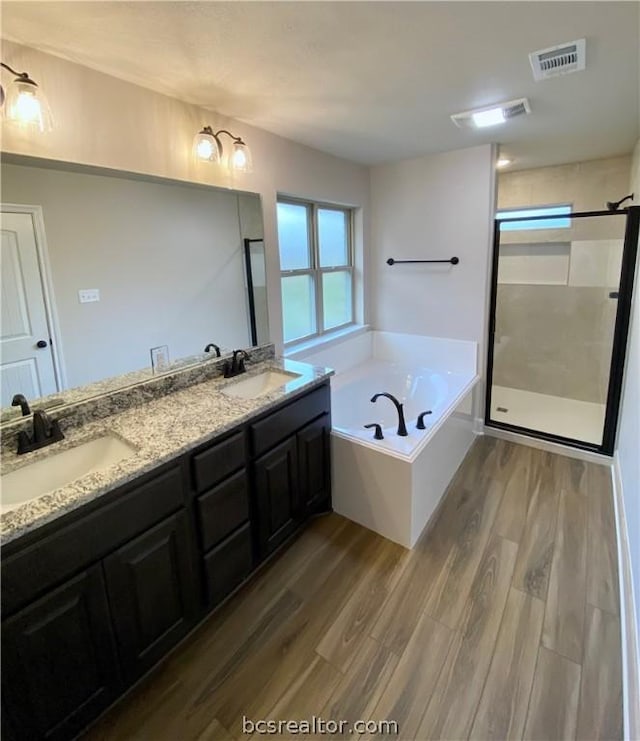 bathroom with wood-type flooring, vanity, and independent shower and bath