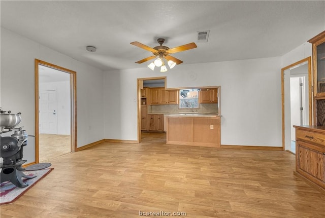 kitchen with kitchen peninsula, light wood-type flooring, ceiling fan, and sink