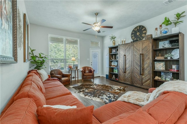 living room with ceiling fan, wood-type flooring, and a textured ceiling