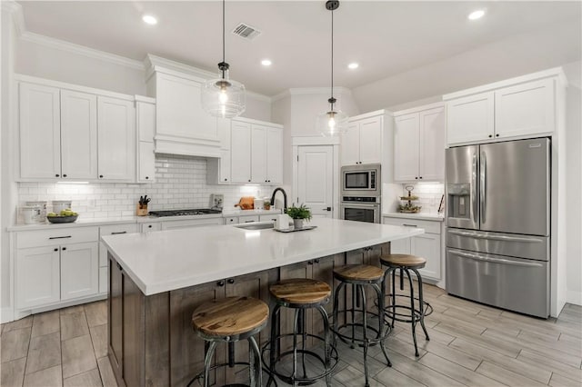 kitchen with sink, white cabinetry, decorative light fixtures, an island with sink, and stainless steel appliances