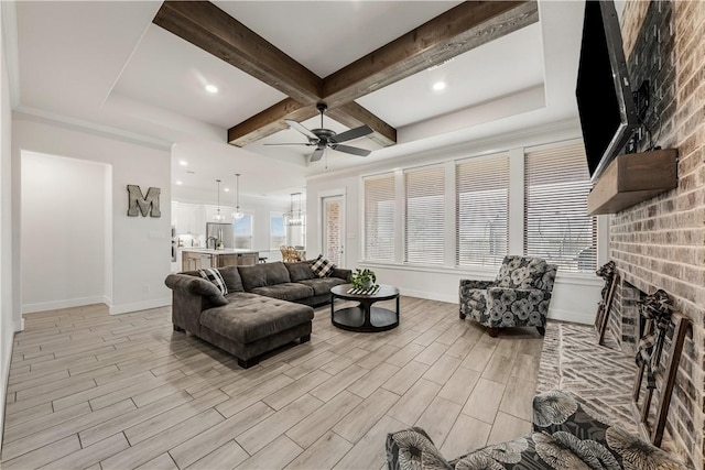 living room with coffered ceiling, sink, beamed ceiling, ceiling fan, and a fireplace