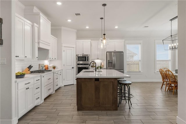 kitchen featuring appliances with stainless steel finishes, a kitchen island with sink, pendant lighting, and sink