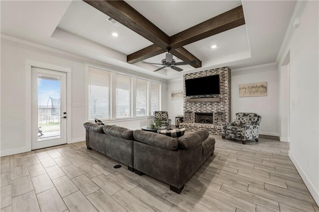 living room featuring coffered ceiling, crown molding, a brick fireplace, ceiling fan, and beam ceiling