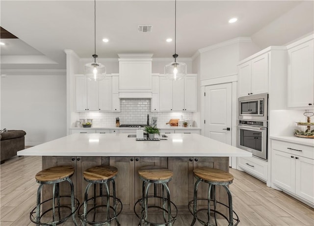 kitchen with appliances with stainless steel finishes, a large island, and pendant lighting