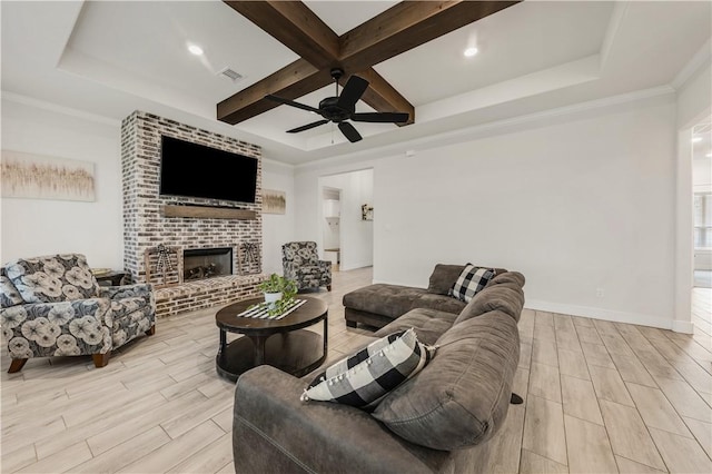 living room featuring beamed ceiling, ornamental molding, coffered ceiling, ceiling fan, and a brick fireplace