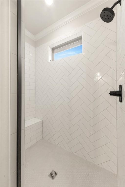 bathroom with ornamental molding and a tile shower