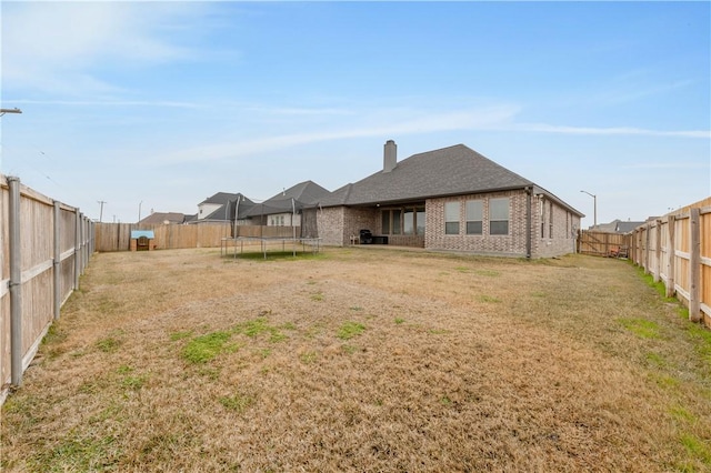 back of house featuring a trampoline and a yard