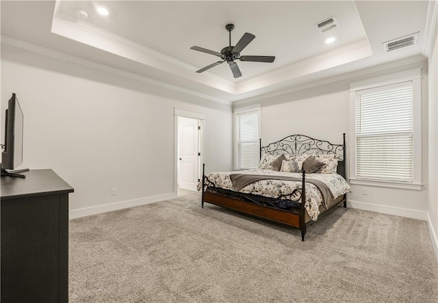 bedroom featuring crown molding, light colored carpet, and a tray ceiling