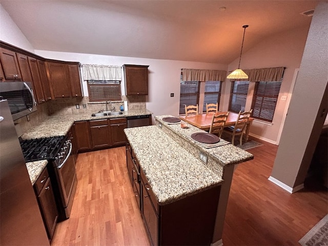 kitchen featuring appliances with stainless steel finishes, backsplash, sink, a kitchen island, and lofted ceiling