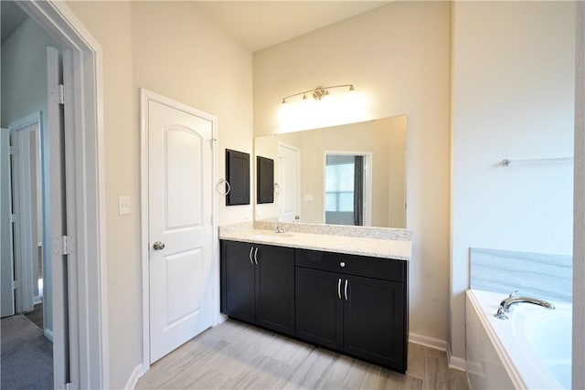 2135 Dumfries Dr, Bryan, TX 77807 - full bath featuring vanity, a bath, wood finished floors, and baseboards