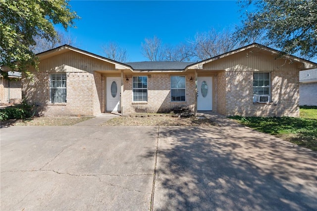 ranch-style house featuring brick siding and cooling unit