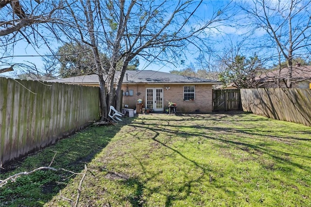 view of yard featuring a fenced backyard and french doors