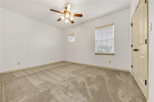 empty room featuring baseboards, a ceiling fan, and light colored carpet