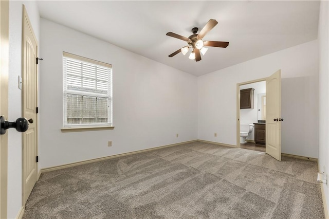 unfurnished bedroom featuring ensuite bathroom, ceiling fan, baseboards, and light carpet