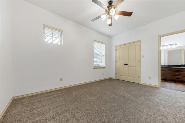 unfurnished bedroom with carpet flooring, ensuite bath, and baseboards