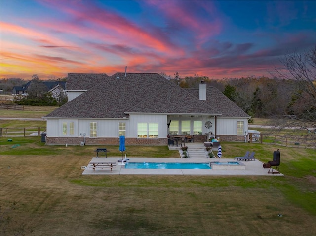 back house at dusk with a patio area and a yard