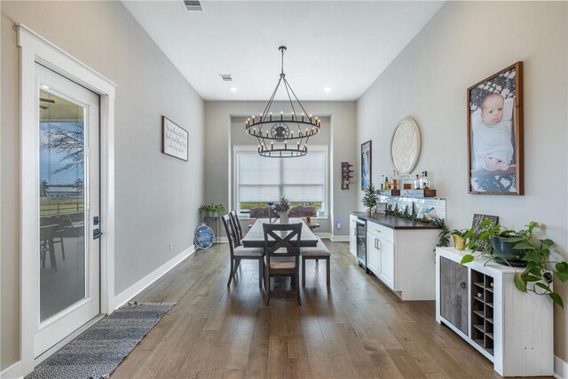 dining room with hardwood / wood-style floors, an inviting chandelier, and wine cooler