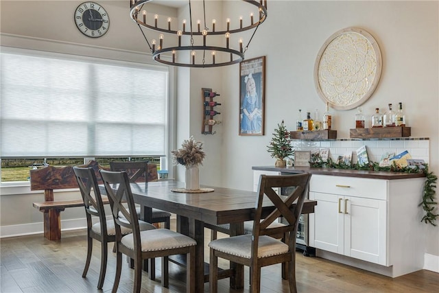 dining area with bar area, light wood-type flooring, and a chandelier