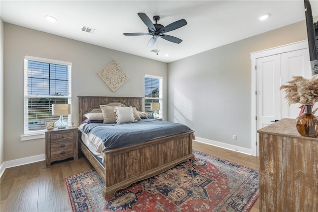 bedroom featuring dark hardwood / wood-style floors, multiple windows, and ceiling fan