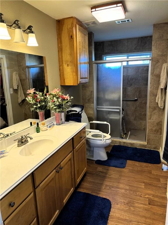 bathroom featuring vanity, hardwood / wood-style flooring, toilet, and an enclosed shower