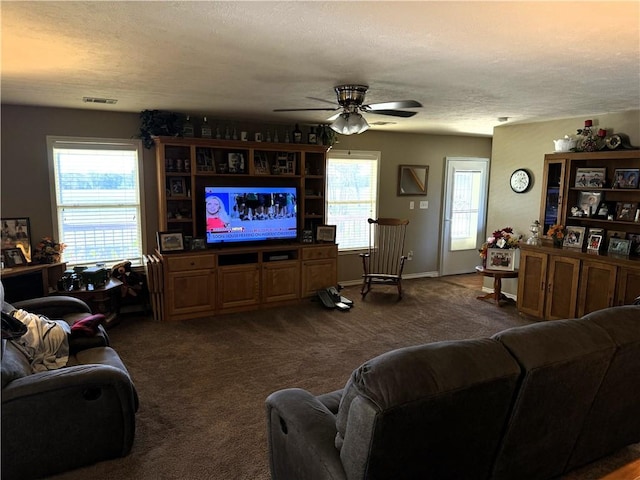 living room featuring ceiling fan, a textured ceiling, and dark colored carpet