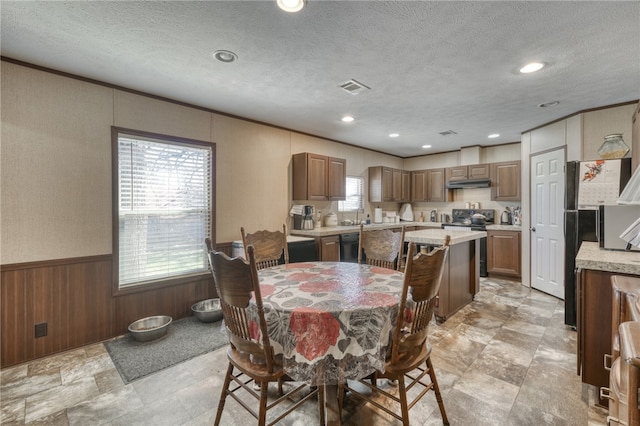 2095 Fm 1452 W, Madisonville, TX 77864 - dining area featuring a wainscoted wall, wooden walls, a textured ceiling, recessed lighting, and light stone finish floors