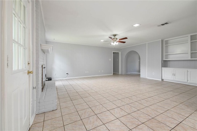 1011 Val Verde Dr, College Station, TX 77845 - spare room featuring arched walkways, a ceiling fan, a brick fireplace, ornamental molding, and light tile patterned flooring